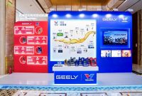 A display booth featuring Valvoline GEELY collaboration, showcasing co-developed lubricants and a timeline of their partnership, with product bottles arranged on a central table.