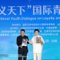 Li Zijun (right), a scholar of the Chinese Theatre Literature Society, displays a photo of his grandfather, Li Hongchun, portraying the legendary Chinese figure Guan Gong during the International Youth Dialogue on Loyalty and Honor Without Borders in Yuncheng, Shanxi province, on Wednesday. [Photo by Zhu Xingxin/China Daily]